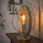 Tafellamp Roxy in beige met draaibare metalen ringen, brandend op een dressoir in een sfeervol interieur.