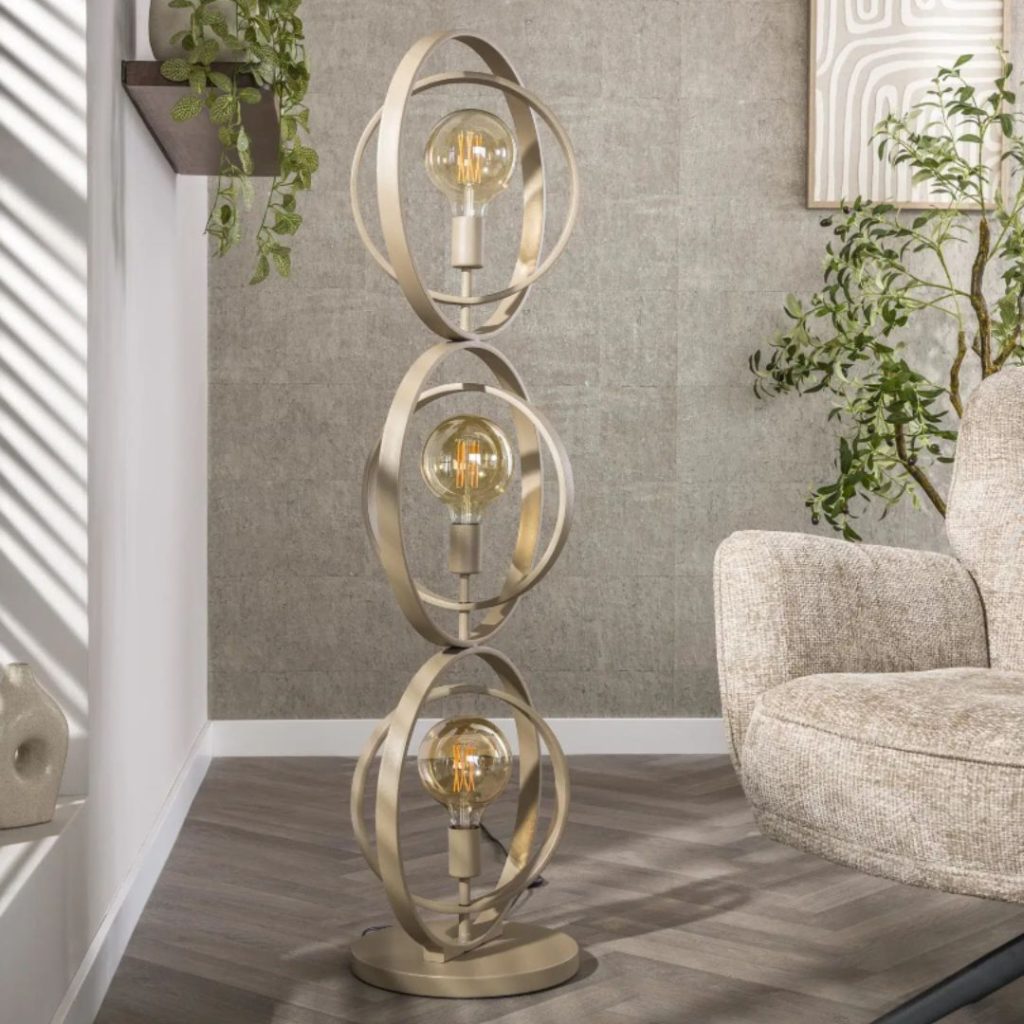 vloerlamp in beige met metalen ringen naast een stoel in een rustig interieur terwijl de lamp uit staat.