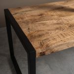 Detail foto van eettafel Dominique van HUUS, gemaakt van massief onbewerkt mangohout en zwart metaal.