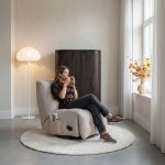 Moderne vrouw op de beige relax fauteuil Zen van HUUS in een japandi interieur.
