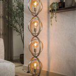 Beige vloerlamp met metalen ringen die branden. Getoond in warm interier