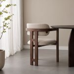 Achterkant van eetkamerstoel Japandi met armleuning met een walnoot kleurig frame en een taupe kleurige zitting.
